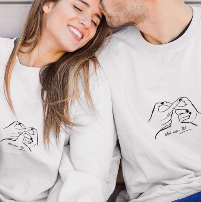 Pareja usando sudaderas a juego en color blanco con diseño en color negro