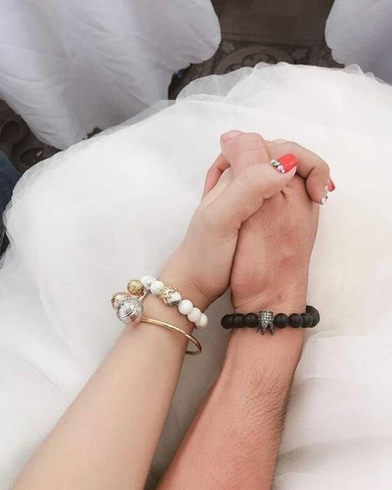 Pareja tomada de las manos usando pulseras gemelas