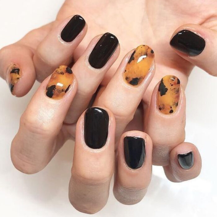 Manicura con diseño carey en varios dedos y esmalte negro en el resto