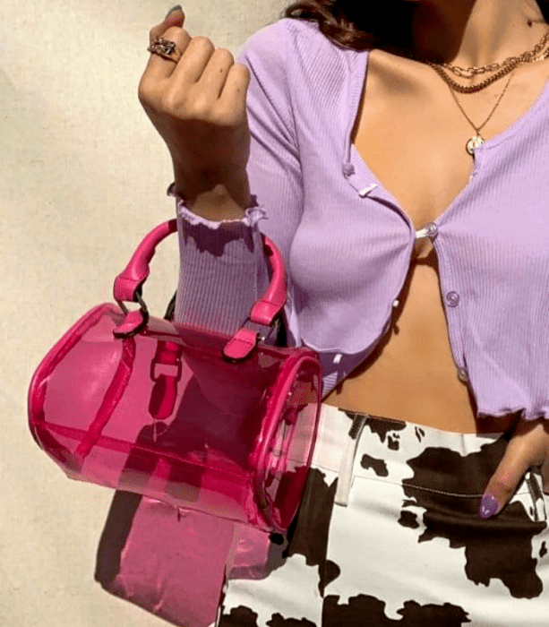 bolso rosa de plástico semi transparente, pantalones blancos con manchas negras, cárdigan morado lila