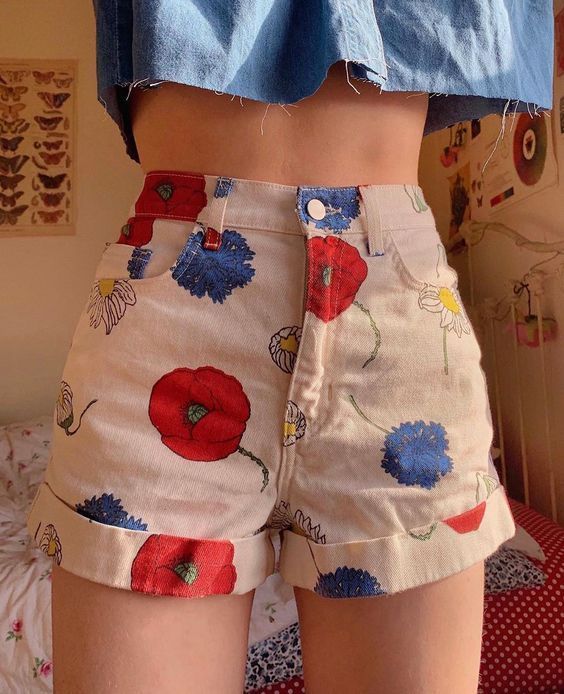 chica llevando short corto en color blanco con flores azules y rojas