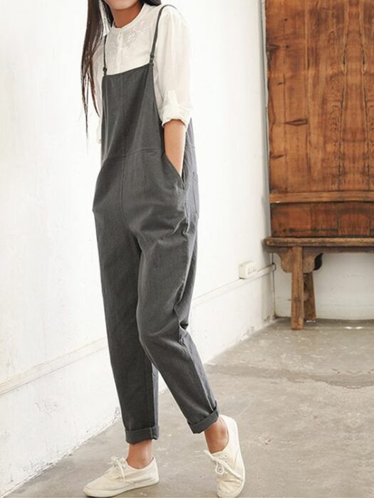 Chica usando jumpsuit color gris, con blusa blanca debajo y tenis del mismo color