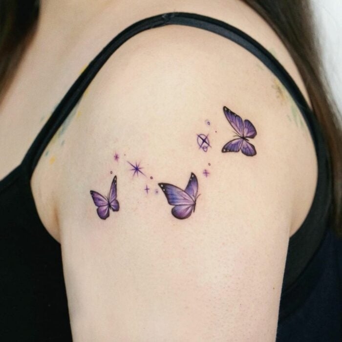 Tatuaje con tres mariposas miniatura en tonos morados revoloteando;  15 Bellos tatuajes con mariposas para iniciar una metamorfosis