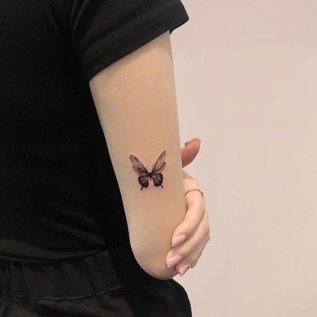 chica mostrando un tatuaje de mariposa en el coda en tono negro;  15 Bellos tatuajes con mariposas para iniciar una metamorfosis