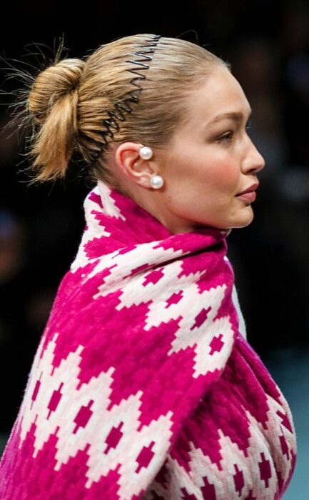 Gigi Hadid modelando un atuendo rosa con una diadema de zigzag 