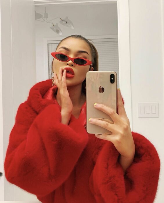 Chica tomandose una selfie mientras usa un outfit rojo y gafas de color rojo con negro 