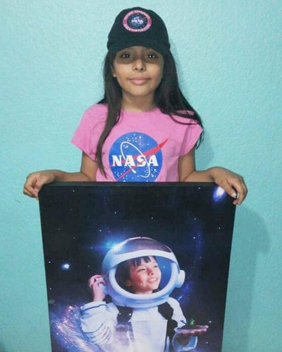 Adhara Pérez mostrando un cuadro donde ella es astronauta