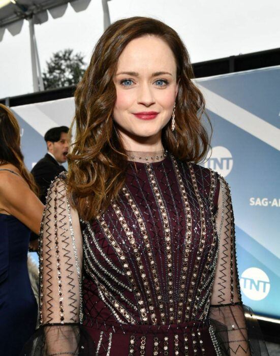 Alexis Bledel usando un vestido negro de manga larga con transparencias, y llevando el cabello suelto