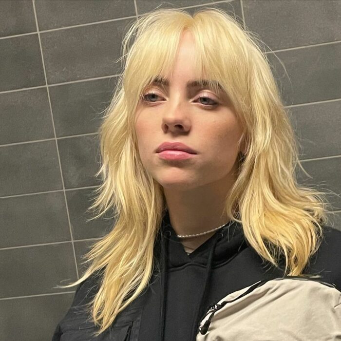 Billie Eilish mostrando su nuevo color de cabello rubio con flecos 