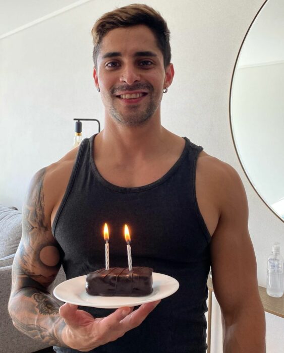 Chico festejando su cumpleaños y sosteniendo un pequeño pastel con una velita 