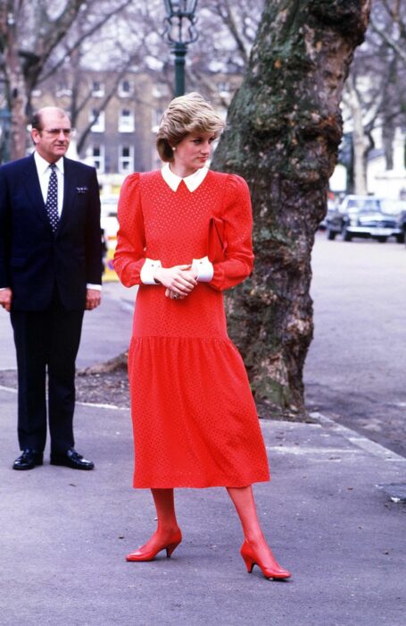 Diana de gales usando un vestido de color rojo con medias del mismo color y zapatos 