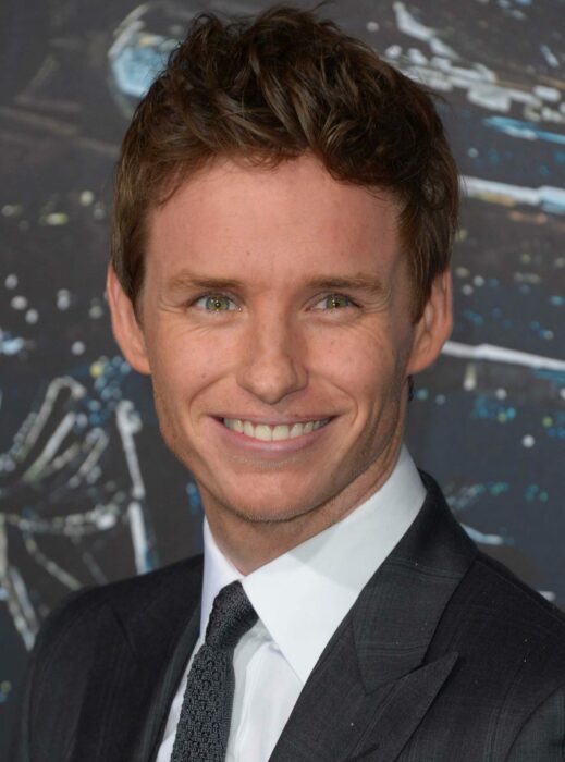 Eddie Redmayne sonriendo y usando un traje de gala