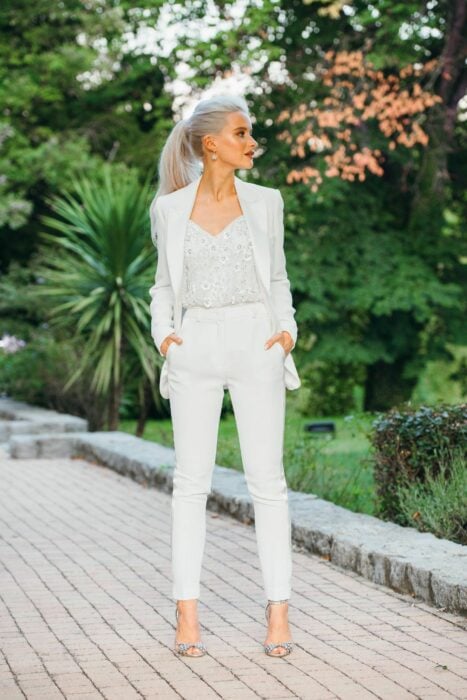 Chica usando un traje de color blanco con un top lleno de brillos 