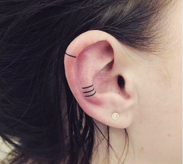 Chica con un tatuaje en la oreja en forma de líneas en diferentes ángulos