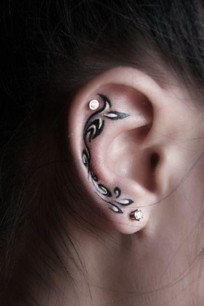 Chica con un tatuaje en la oreja en forma de olas en color blanco con negro