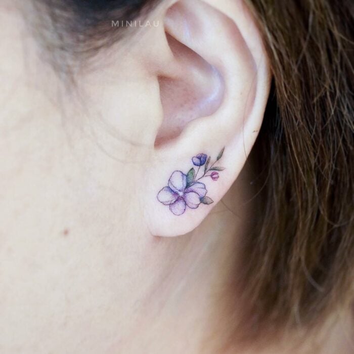 Chica con un tatuaje en la oreja en forma de flor en el lóbulo de la oreja