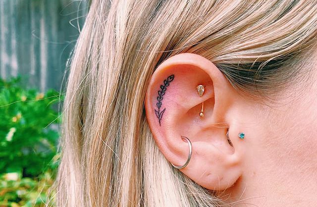 Chica con un tatuaje en la oreja en forma de flor de lavanda