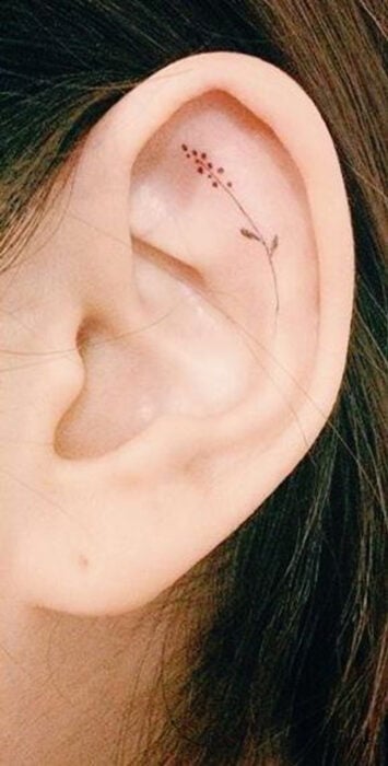 Chica con un tatuaje en la oreja en forma de flor pequeña