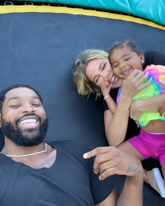 Khloe Kardashian y Tristan Thompson recostados en una cama elastica jugando con su hija True