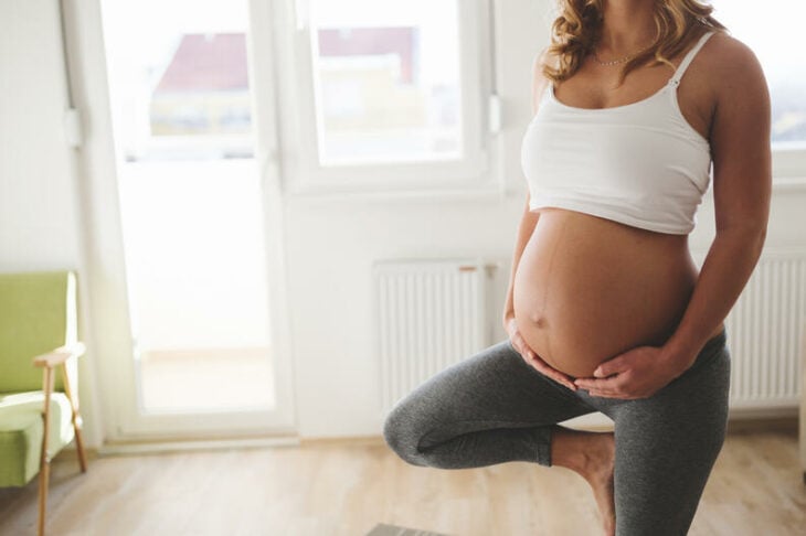 Mujer embarazada, mostrando línea alba en vientre, haciendo yoga