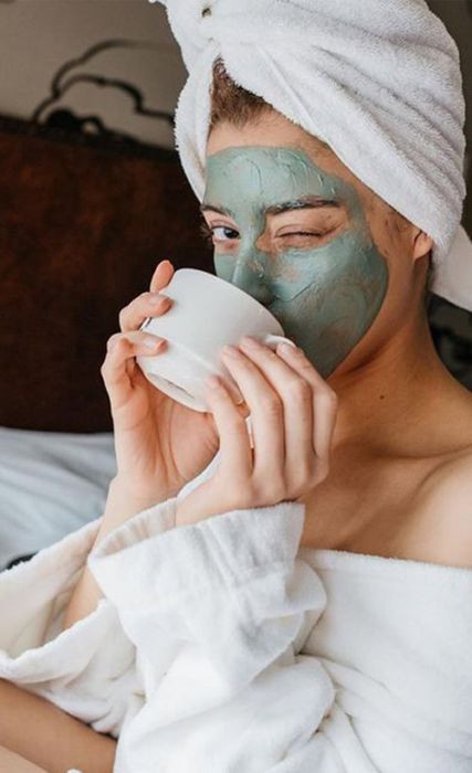 Chica llevando mascarilla; Mascarillas con huevo para una piel bonita en el rostro y bebiendo té, 