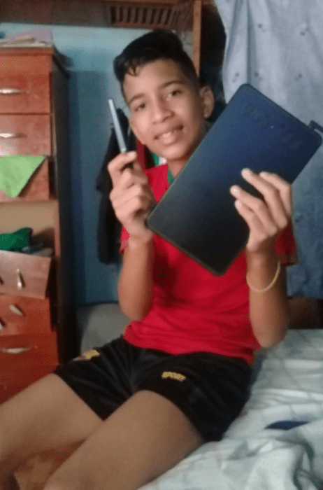 Niño Samuel Mendoza posando para una fotografía mientras sostiene una tableta 