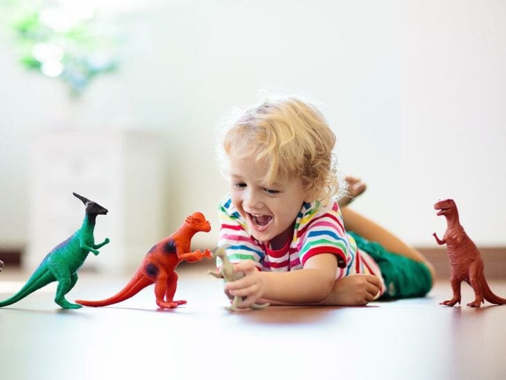 Niño sentado jugando con diferentes dinosaurios 