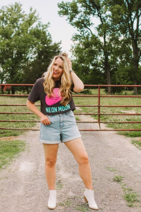 Chica usando unos mom shorts acompañados de una camiseta estampada y botas vaqueras 