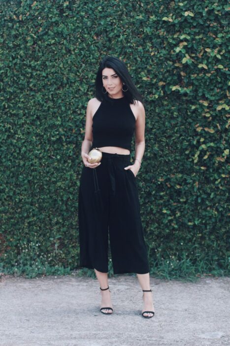 Chica usando un top negro y unos pantalones culottes con sandalias