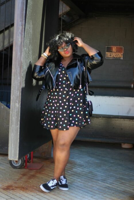 Chica usando un vestido de color negro con puntos de colores, chaqueta de cuero y tenis vans