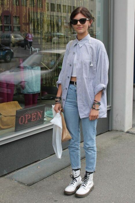 Chica usando jeans, botas Dr. Martens y una blusa larga de color azul 