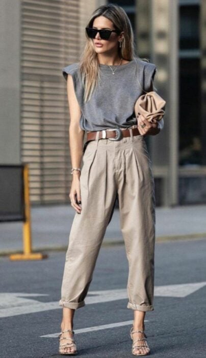 Chica usando unos pantalones de color café con una blusa gris y tacones 