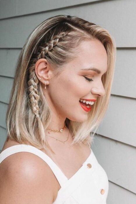 Chica de cabello corto, rubio con partido de lado y trenza pegada de un lado