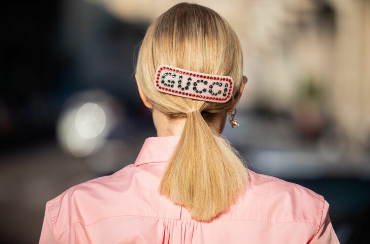 Chica con una coleta baja sujetada con un broche que dice Gucci