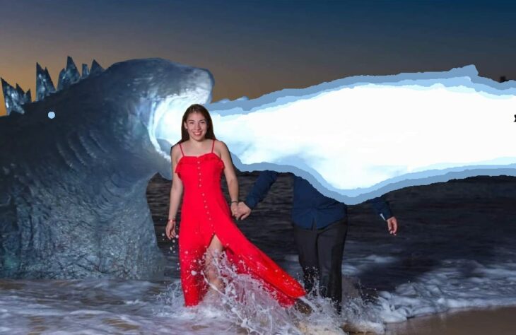 Edición de Godzila en la foto de una pareja que camina por la playa