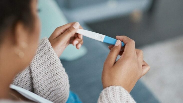 Chica con una prueba de embarazo en sus manos esperando el resultado