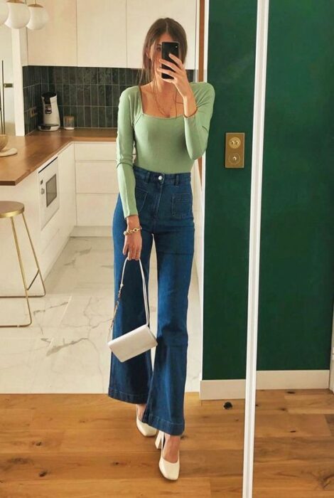 Chica usando tacones con jeans acampanados y blusa de color verde