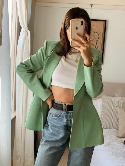 Chica usando jeans, crop top blanco y blazer color verde