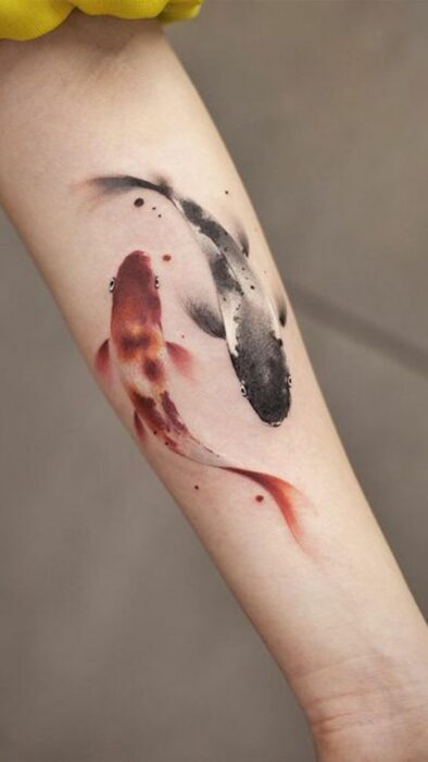 Tatuaje de peces koi en la zona interna del brazo