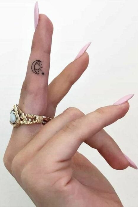 Tatuaje de sol y luna en el lateral del dedo medio