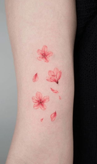 Chica con un tatuaje en el brazo en forma de flores de cerezo 