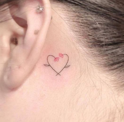 Chica con un tatuaje atrás de la oreja con un corazón y flores 