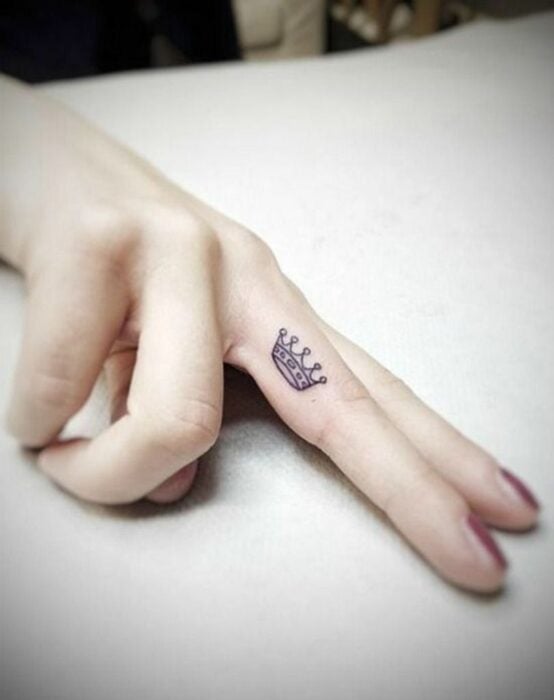 Chica con un tatuaje en forma de corona en el dedo medio