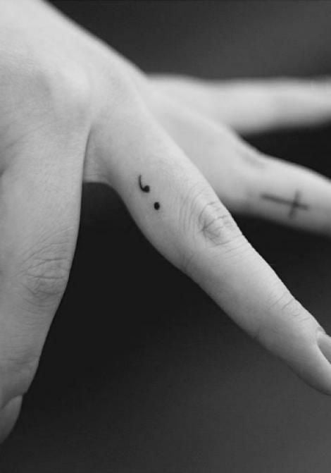 Chica con un tatuaje en forma de punto y coma en el dedo 
