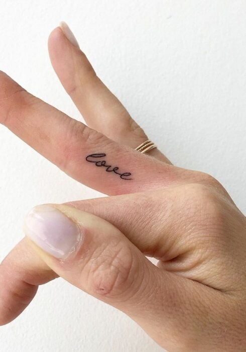 Chica con un tatuaje en letras love en el dedo medio 