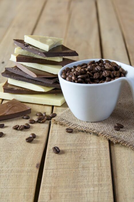 Chocolate en barra junto a una taza de granos de café; Tinte de café y chocolate, el secreto para unas cejas marcadas y gruesas