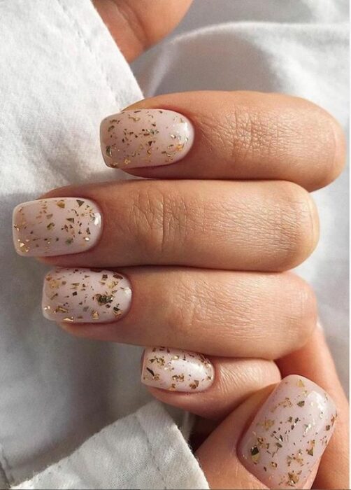 Manicura con base nude y detalles con glitter dorado