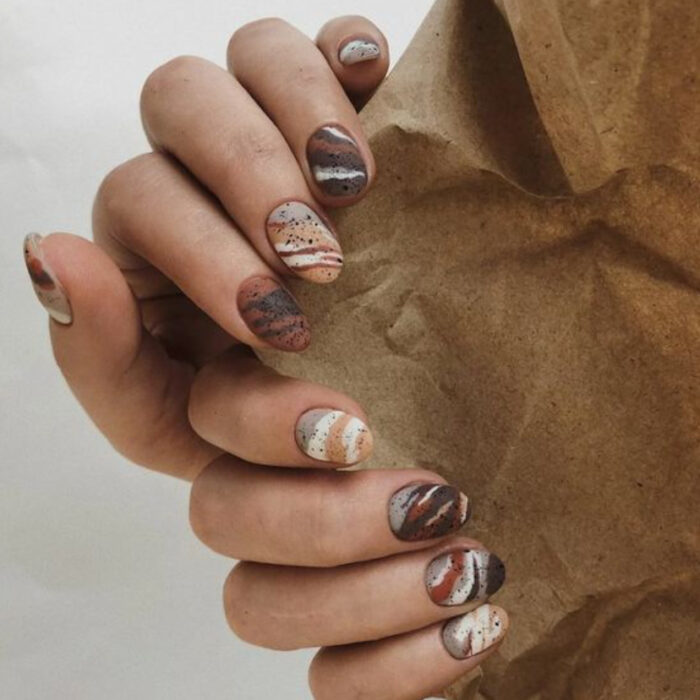 Manicura con tonos café con diseño de líneas