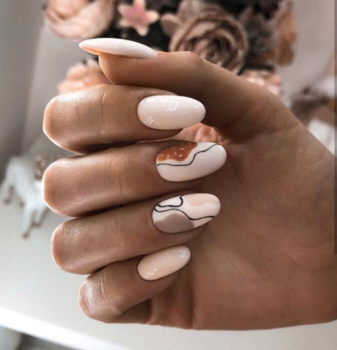 Uñas en base beige con detalles en café y líneas negras