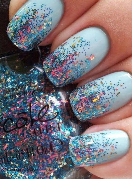 Manicura con fondo azul cielo con glitter de color tornasol 